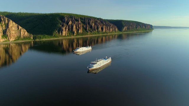 Flight above Lena river pillars beautiful sunset reflection in water. Two vessel cruise ships floats near cliffs rocks weathering formation. Natural wonder world heritage Russia Siberia. Open space