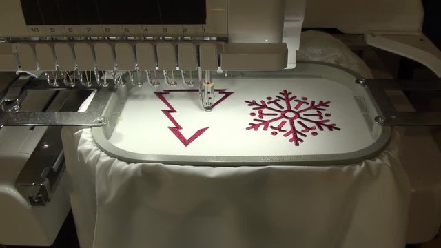 embroidery machine work at the factory on white material dark red thread snowflake design
