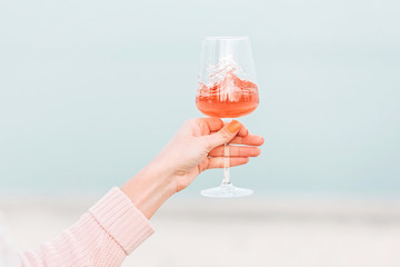 Glass of rose wine in female hand against the seashore.