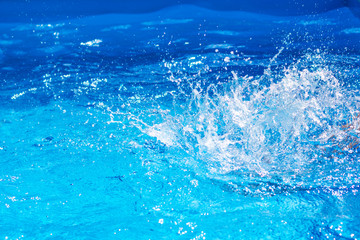 Splashes of clear blue fresh water in pool, air bubbles, water drops, sea wave on blue background...