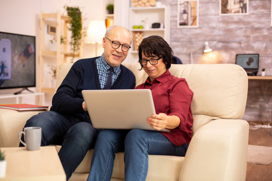 Elderly old couple using modern laptop to chat with their grandson