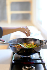 Close up hand and Spicy stir fried pork with red curry paste in pan.