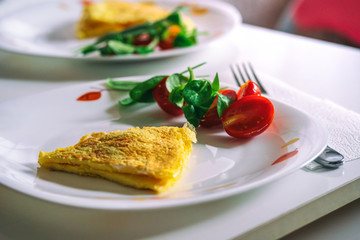 Healthy, hearty breakfast with fried eggs and fresh unprocessed vegetables. Healthy lifestyle concept. White quartet plate on a white table background. Horizontal frame.
