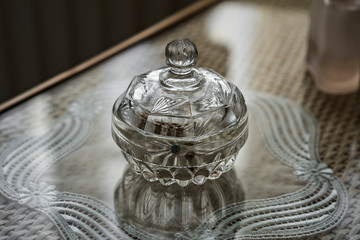 Little ornate cut glass crystal bottle on an interior table in natural light.