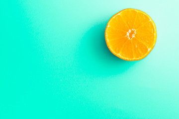 Background with half an orange in the corner with a place for inscription. slice of mandarin on a turquoise background.