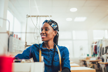 Young african textile worker sewing on production line.
