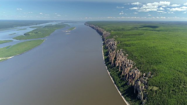 Helicopter epic flight Russia Lena pillars rocks formation crag. Widest river bed Lena attraction Yakutsk Sakha republic. Taiga green forest. Summer sunny blue sky clouds horizon 4K