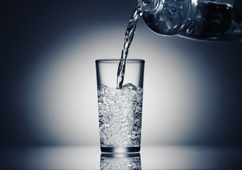 pouring sparkling water in a glass on a dark blue background