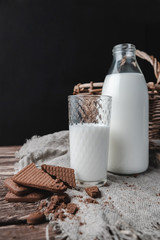 Milk in glass bottle and glass on wooden background