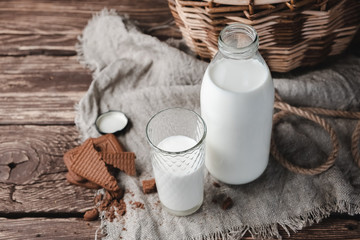 Milk in glass bottle and glass on wooden background