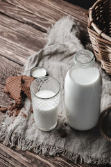 Milk in glass bottle and glass on wooden background