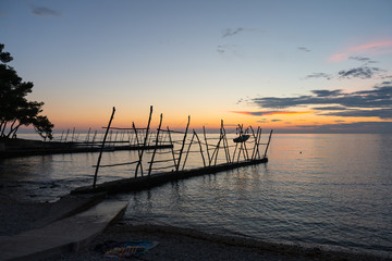 The Savudrija beach at sunset, with the typical wooden cranes of the small dock.