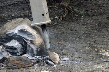 machine with a jackhammer crushes stones