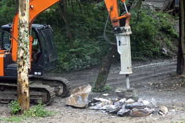 machine with a jackhammer crushes stones