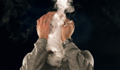 smoking man in e-cigarette smoke on black background