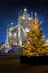 Weihnachten in London: die Tower Bridge bei Nacht mit einem bunt beleuchtetem Weihnachtsbaum davor, Großbritannien © moofushi