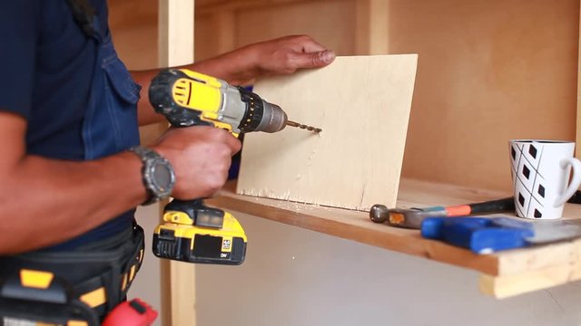 Handyman with headphones works with drill does repair.