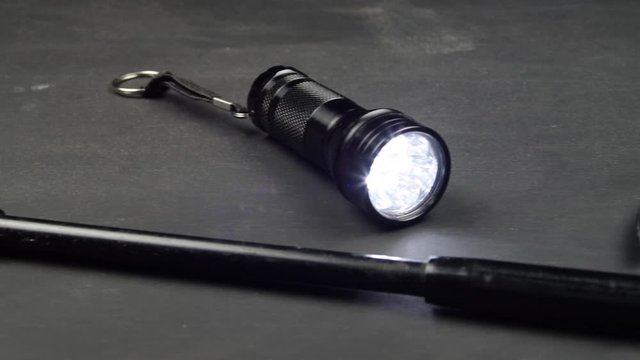 Knife flashlight and baton telescopic on a black surface