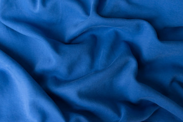 Blue fabric texture background. Textile cloth colored in trend classic blue color of the year 2020. Classic Blue Pantone color. Shallow depth of field, selective focus