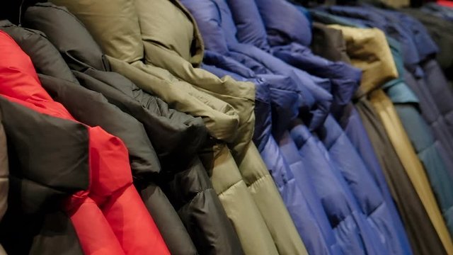 Winter fashion down jackets on a clothes rack in a retail fashion store. Close up.