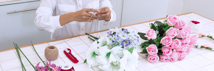 young women business owner florist making or Arranging Artificial flowers vest in her shop, craft and hand made concept