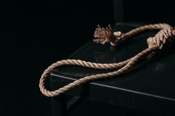 rope noose on chair on black background, suicide prevention concept