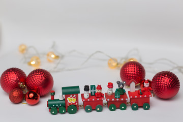 Toy train on a white background with red balls and a shiny garland