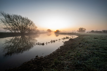 Misty sunrise with reflections on the River Nene in Fotheringhay 