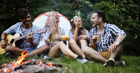 Group of friends camping and sitting around camp fire