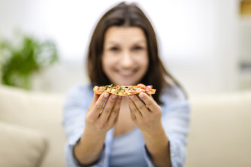 Blurred smiling woman is presenting hot, delicious slice of pizza. Close up. Copy space.