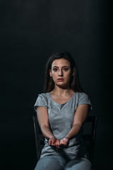 despondent woman looking at camera while holding handful of pills and going to commit suicide isolated on black