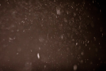 Abstract Snow falls on a dark winter night. Snowflakes bokeh blur effect.