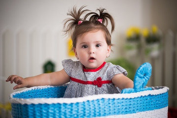 Beautiful little brown-eyed girl sits in basket