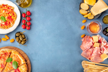 Italian food. Pizza, pasta, cheese, hams, wine and capers, shot from above with a place for text, a flat lay composition