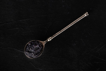 Black caviar on a spoon, shot from the top on a dark background with copy space