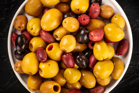 Olives variety. Black, green and brown olives, close-up overhead shot of an assortment on a dark background