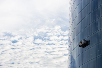 Obraz na płótnie Canvas 10/17/2019 - Bilbao, Spain: skyscraper with washing gondola on sky background. Modern urban buildings concept. Climbing window cleaner in skyscraper. Dangerous work. Worker on office centre facade.