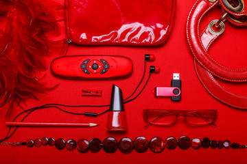 Overhead view of essential beauty items. Woman red accessories, fashion industry, modern life concept, clothes, shoes, gadget, jewelry, cosmetic, other luxury objects on red background.