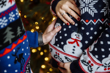 Pregnancy. Close-up photo of the belly of a pregnant girl, which she and her husband gently stroke and hug near a Christmas tree