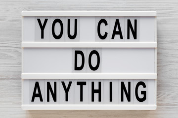 Fototapeta premium 'You can do anything' words on a modern board on a white wooden background, top view. Overhead, from above, flat lay. Close-up.