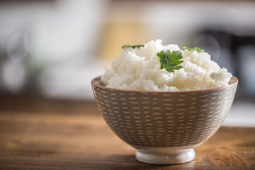 Cooked rice in bowl on kitchen table - close up