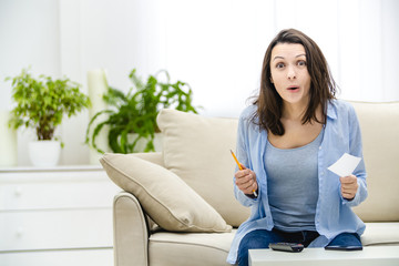 Surprised woman opens her mouth, holding a paper sticker and a pencil in her hands. Copy space.