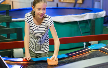 Little girl playing air hockey in amusement park.