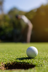 Golfer putting golf ball into hole