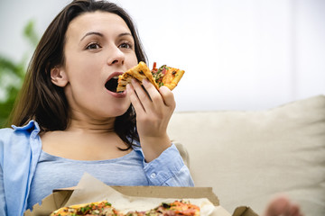 Satisfied and happy woman enjoys eating pizza. Close up. Copy space.
