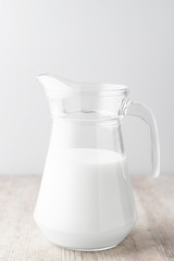 A jug of milk on a wooden table on a white background