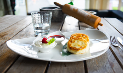 Traditional breakfast with coffee and cheesecakes, cottage cheese pancakes on a plate with syrup and jam.