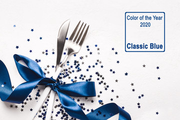 Christmas table setting decorated with classic blue ribbon and stars confetti on white background