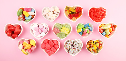 candies with jelly and sugar. colorful array of different childs sweets and treats on pink...