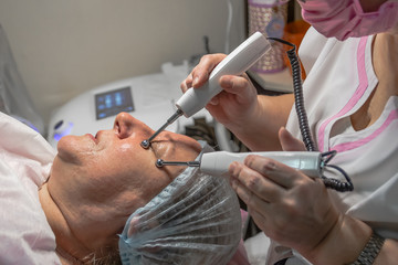 A cosmetic procedure with microcurrent injections in a beauty salon is performed for an aged woman. Improving skin turgor, rejuvenation and healing.